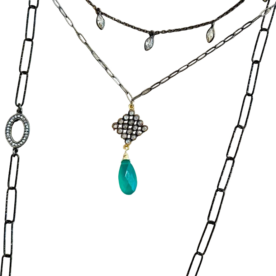 Green onyx briolette necklace with diamond-shaped white topaz charm in sterling silver, shown layered with other necklaces.